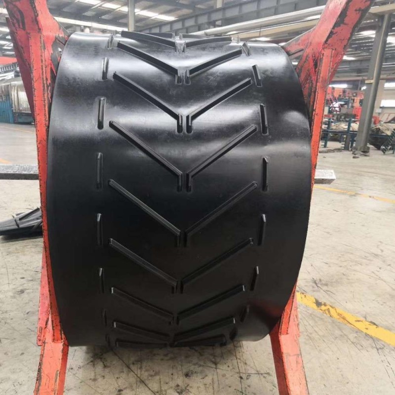 Chevron pattern conveyor belt for inclined material transport